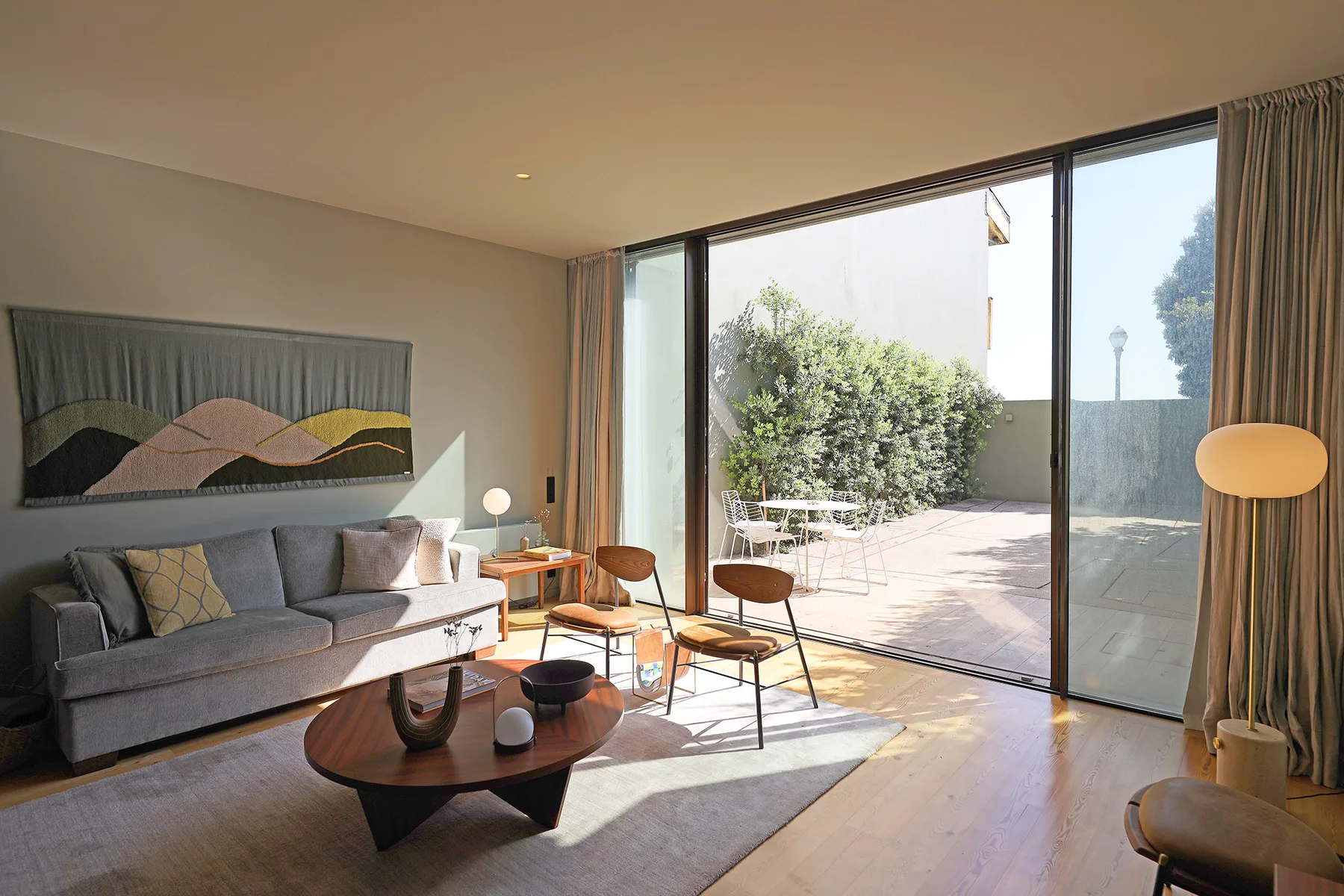 Living room with seating and a large glass door opening onto a sunlit terrace.