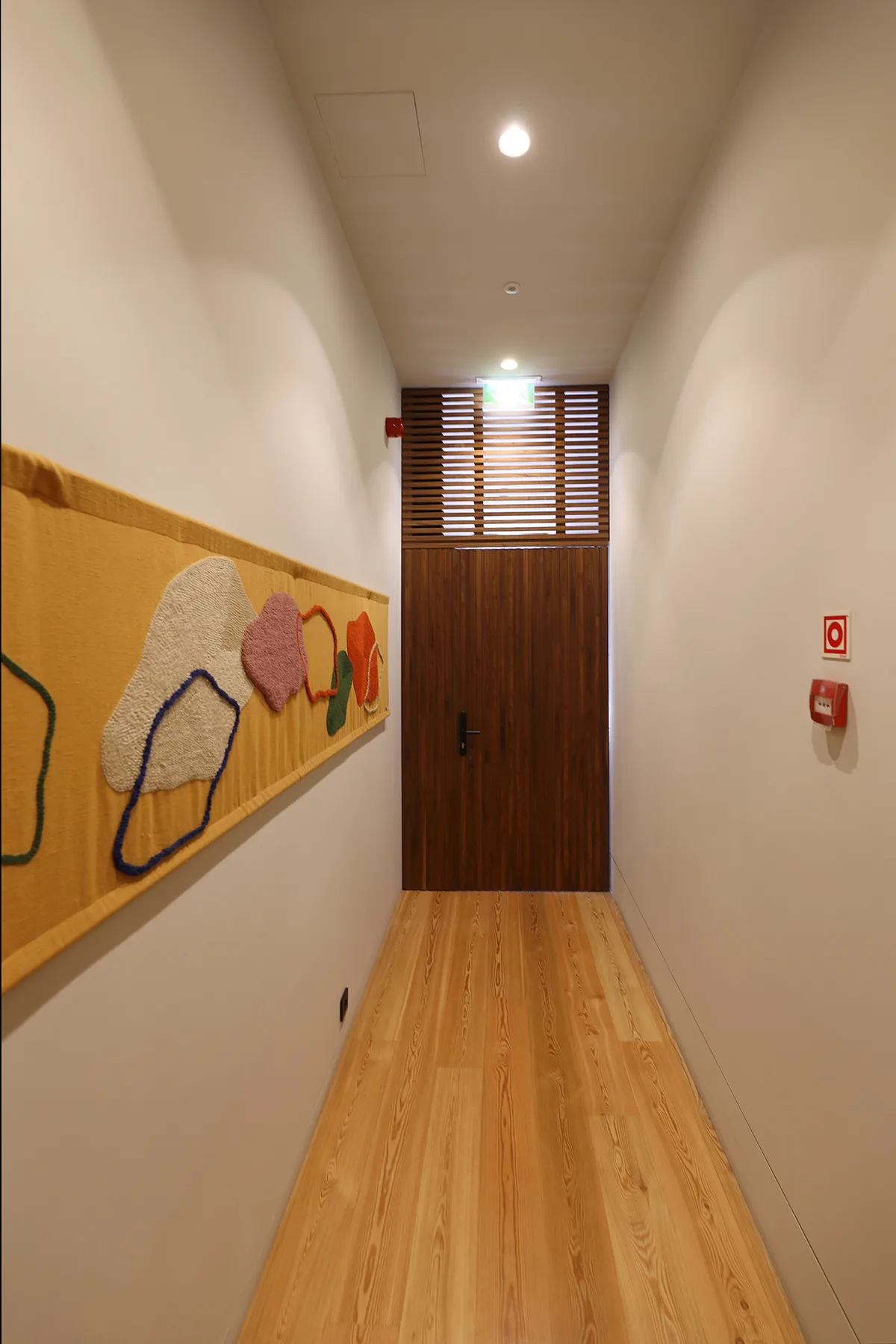 A hallway with wooden flooring and a colorful wall display.