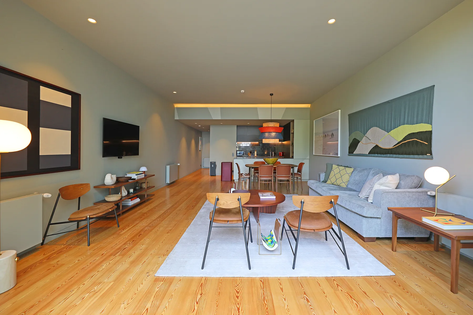 A bright living and dining area with a seating arrangement and kitchen beyond.