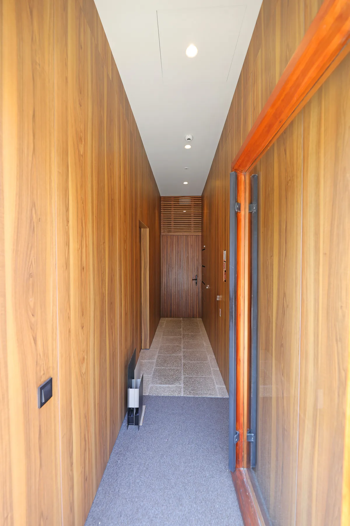 A narrow hallway with wood-paneled walls and a door at the far end.