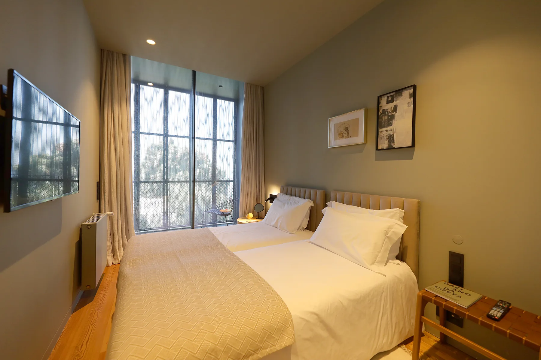 A bedroom with two beds beside tall windows.