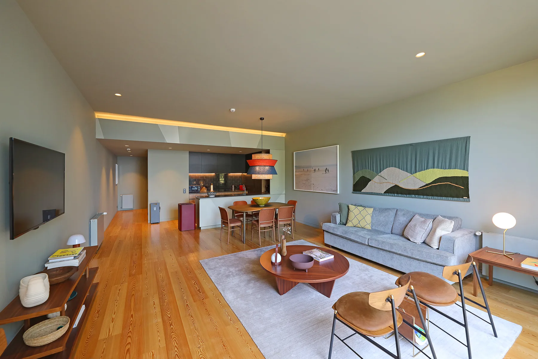 A modern open-plan living room with a dining area and kitchen.