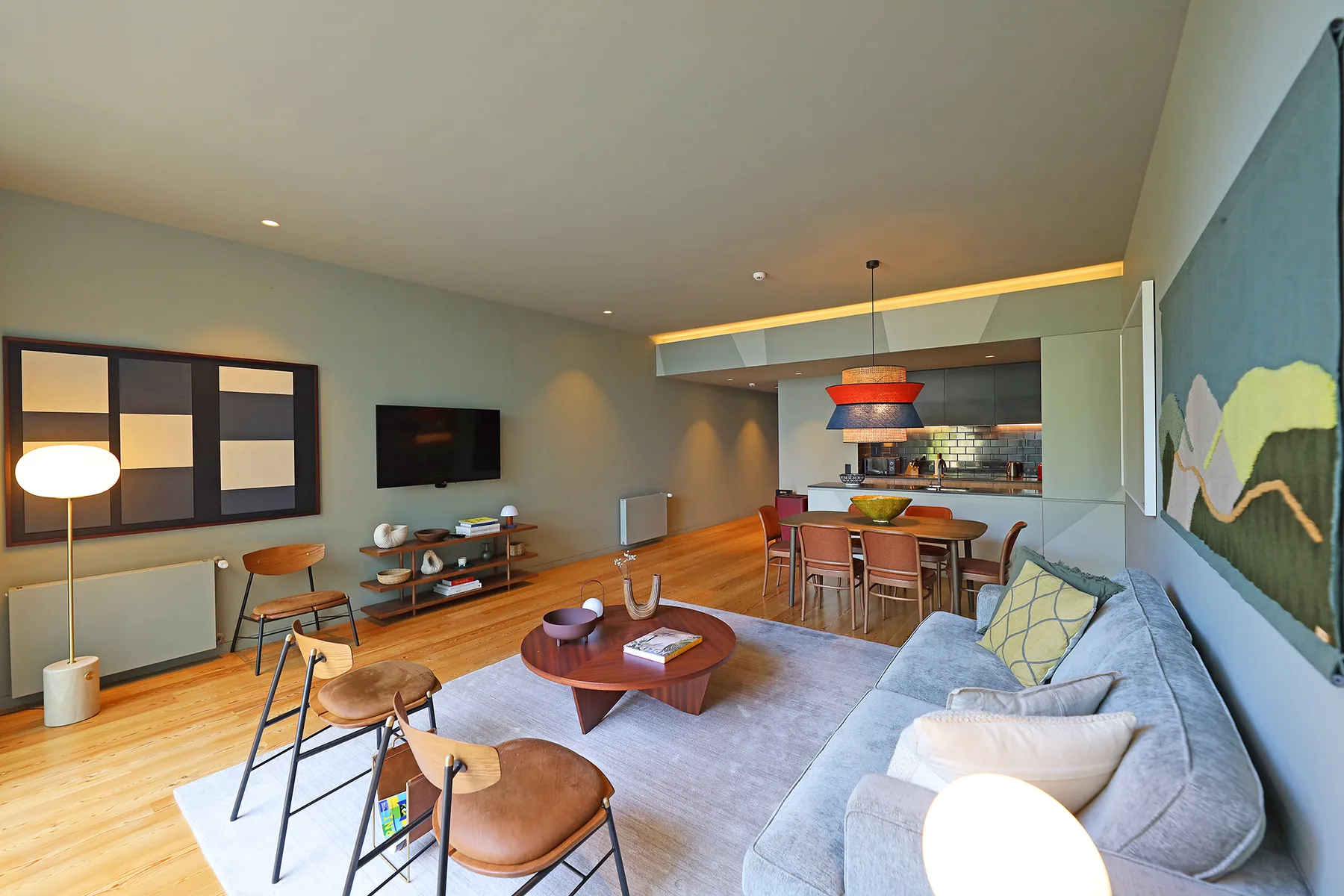 A living room with seating around a coffee table, opening onto a kitchen.