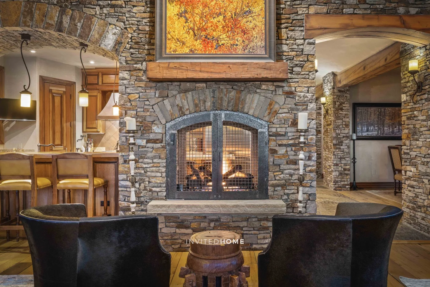 A stone fireplace with a framed autumn landscape anchors a warmly lit living area.