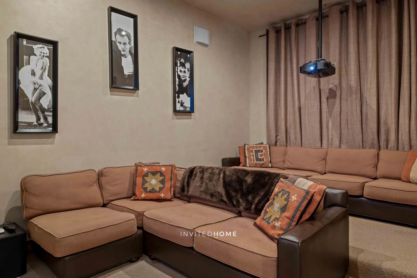 A living room with sectional seating, framed artwork, and curtains.