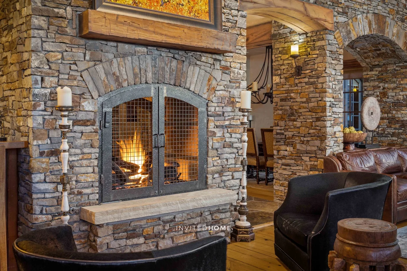 A stone fireplace with a metal screen warms a room with seating.
