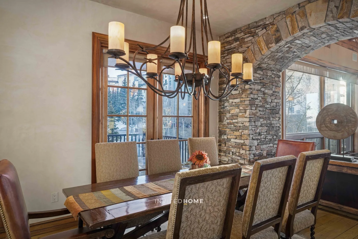 A dining room with a long table and a hanging chandelier.