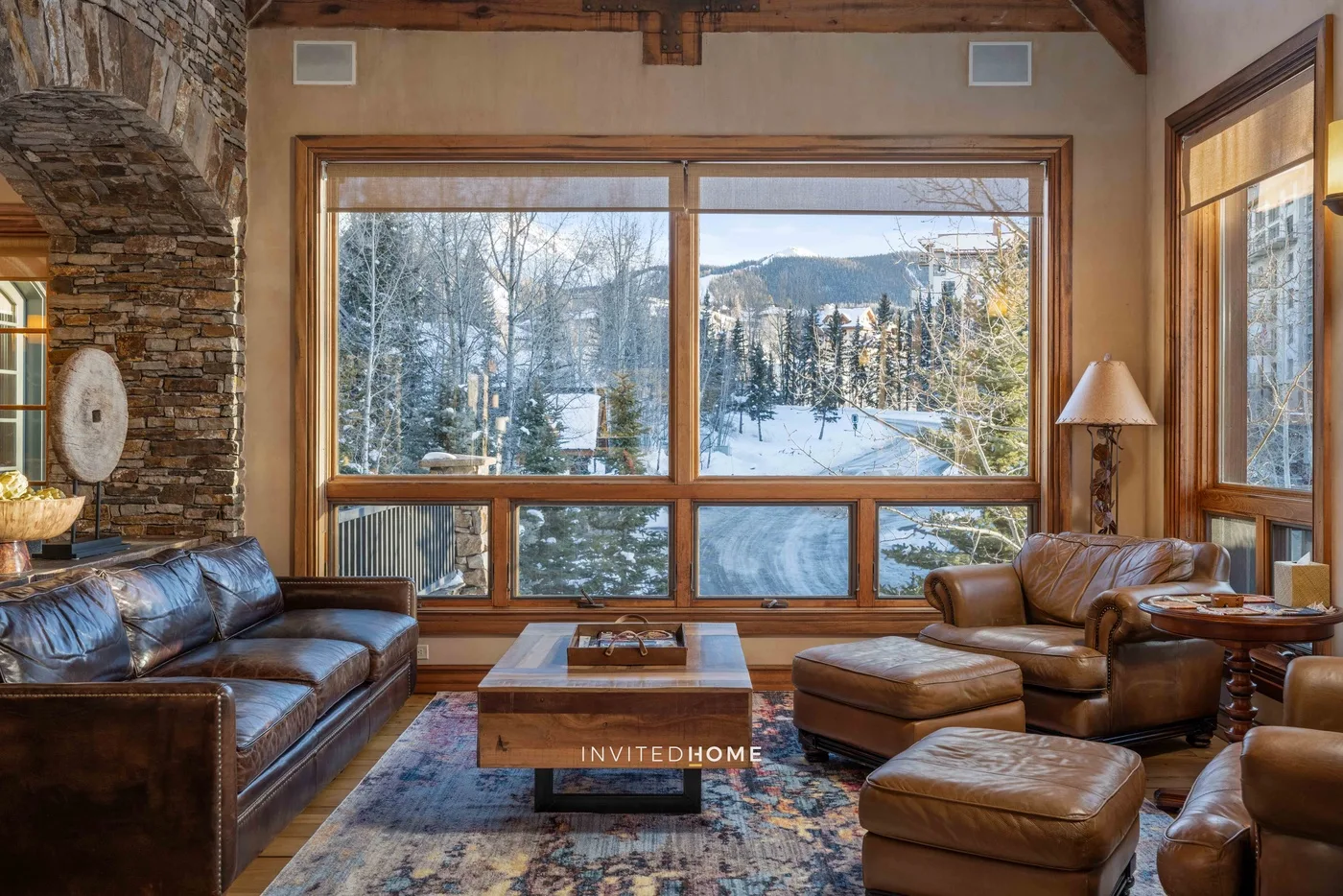 A living room with leather seating and large windows overlooking a snowy landscape.