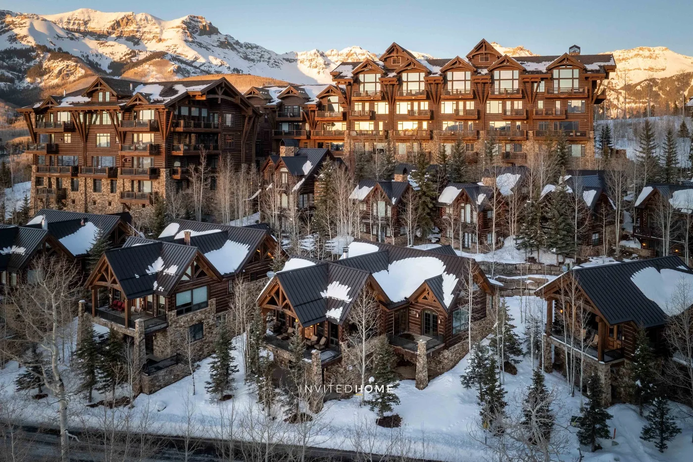 A snowy mountain resort with timber buildings beneath sunlit peaks.