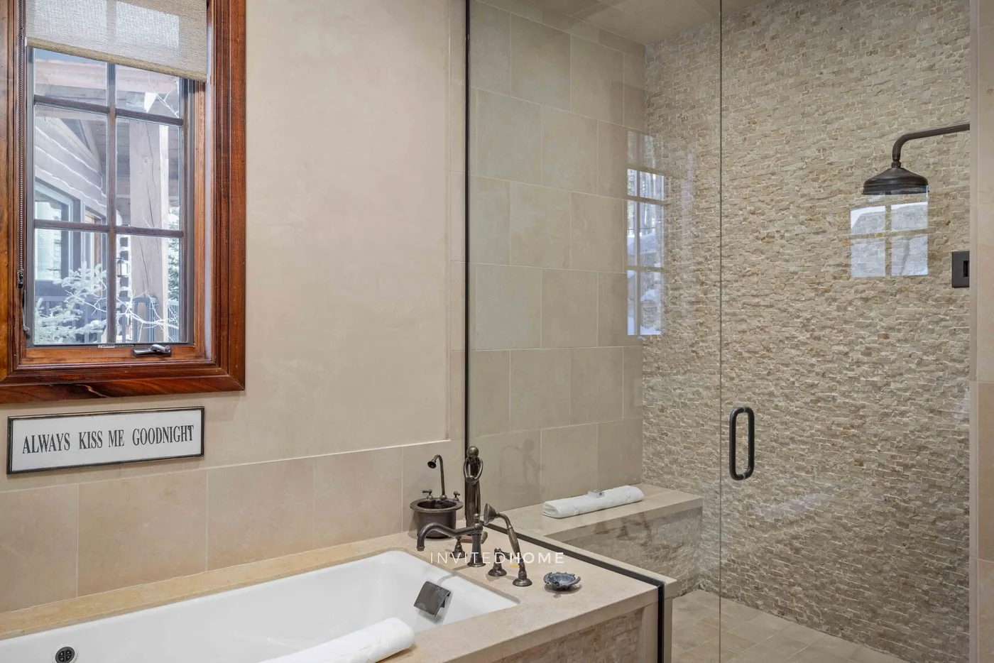 A bathroom with a bathtub beside a glass shower and a window.