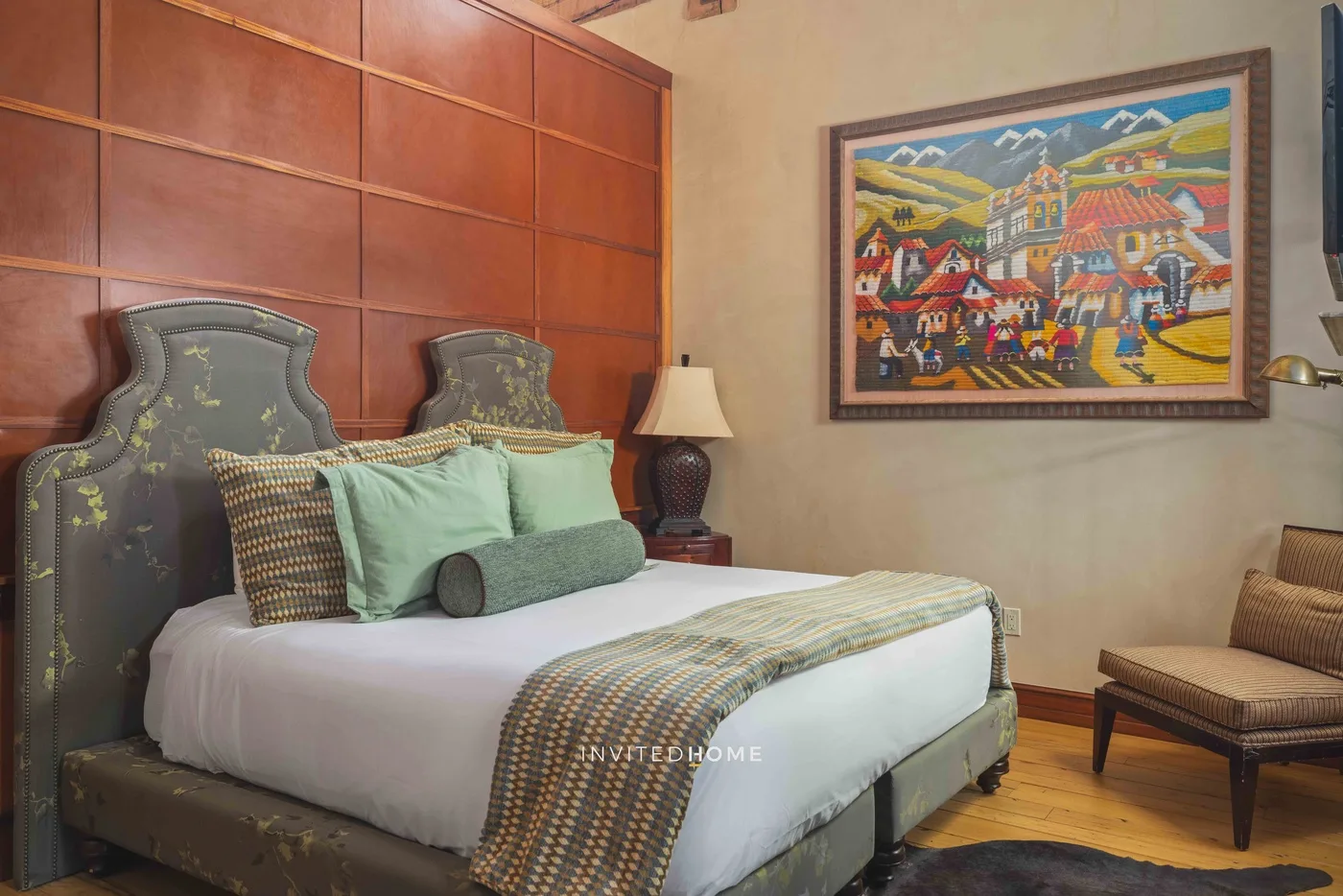 A bedroom with a neatly made bed and colorful framed artwork on the wall.