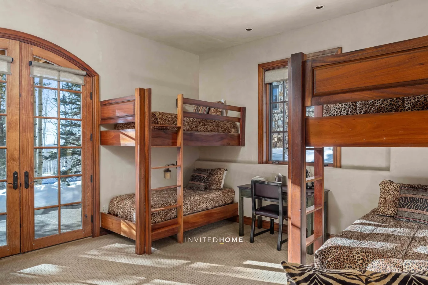 A bedroom with wooden bunk beds and a large glass-paneled door.