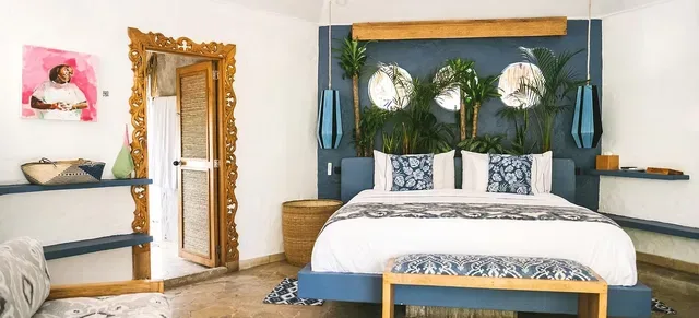 Dormitorio con paredes azules, una cama y plantas tropicales