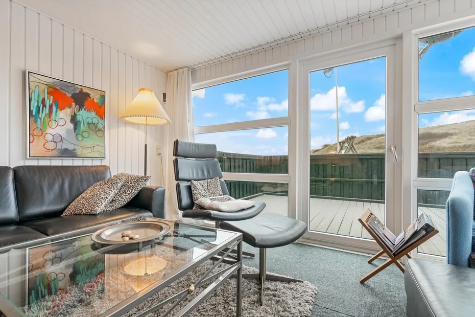 Una sala luminosa con asientos junto a grandes ventanas que dan a una terraza.