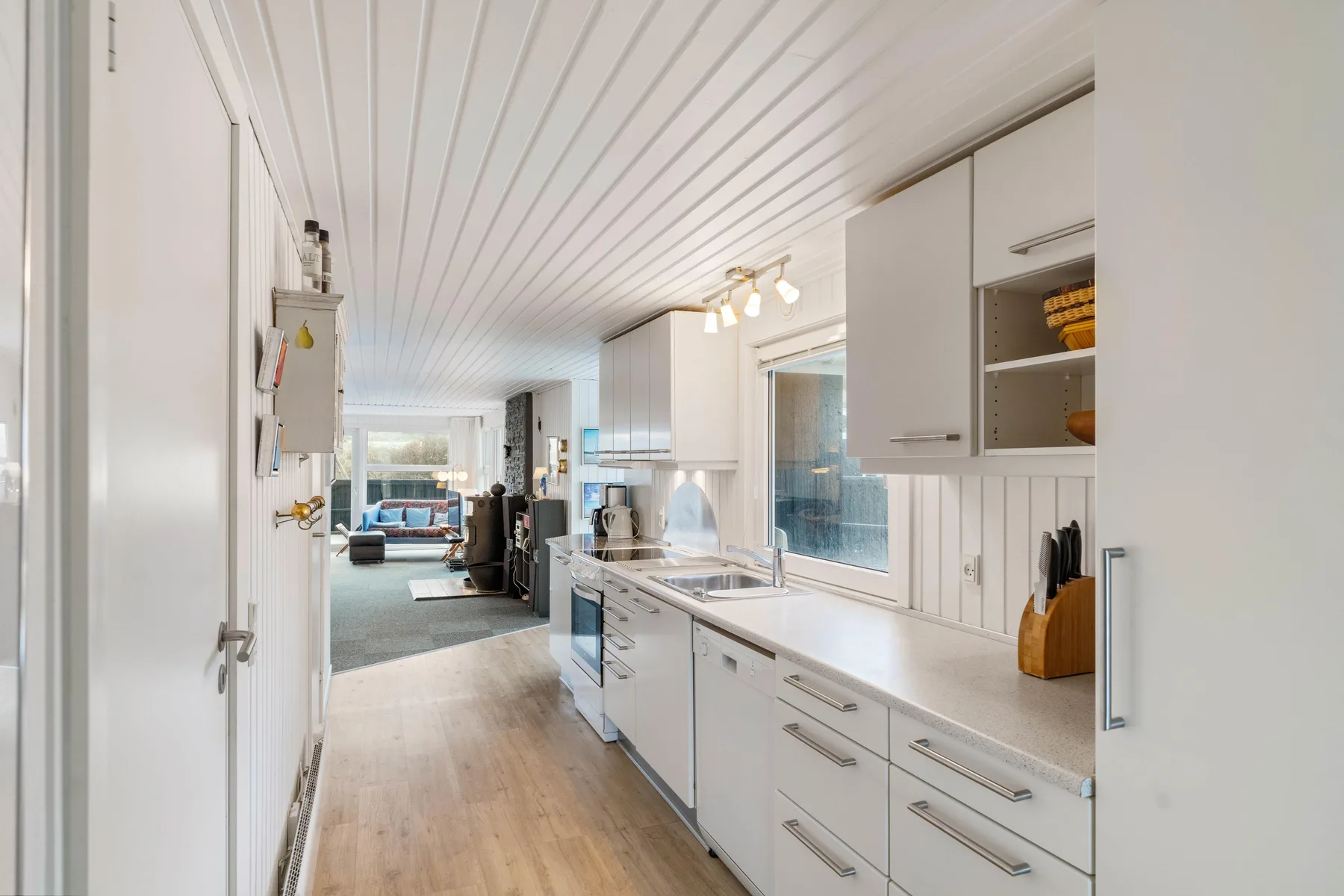 Una cocina luminosa con armarios blancos y una encimera larga.