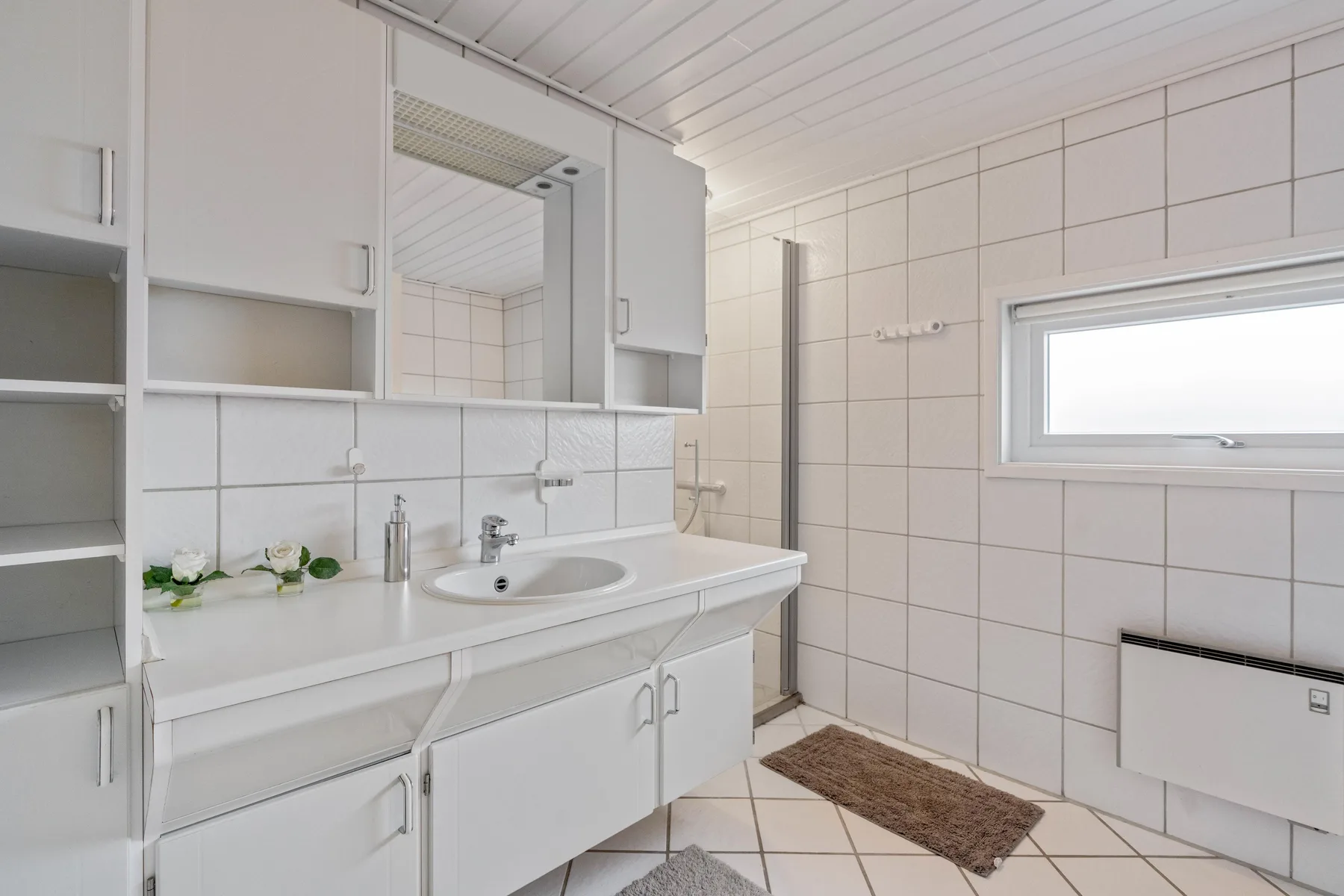 Un baño con azulejos, un lavabo y una ventana pequeña.