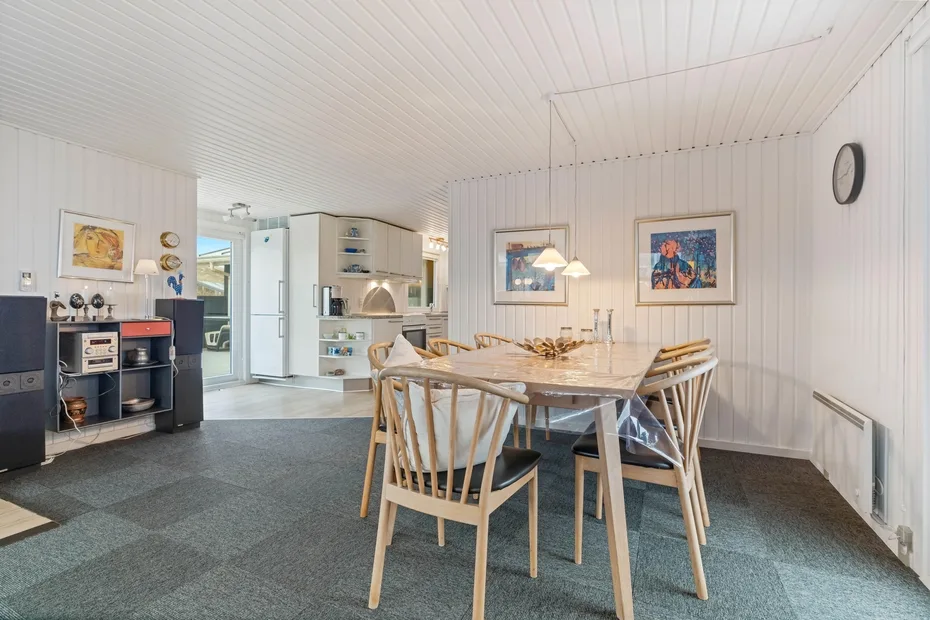 Comedor con una mesa de madera y sillas junto a una cocina abierta.