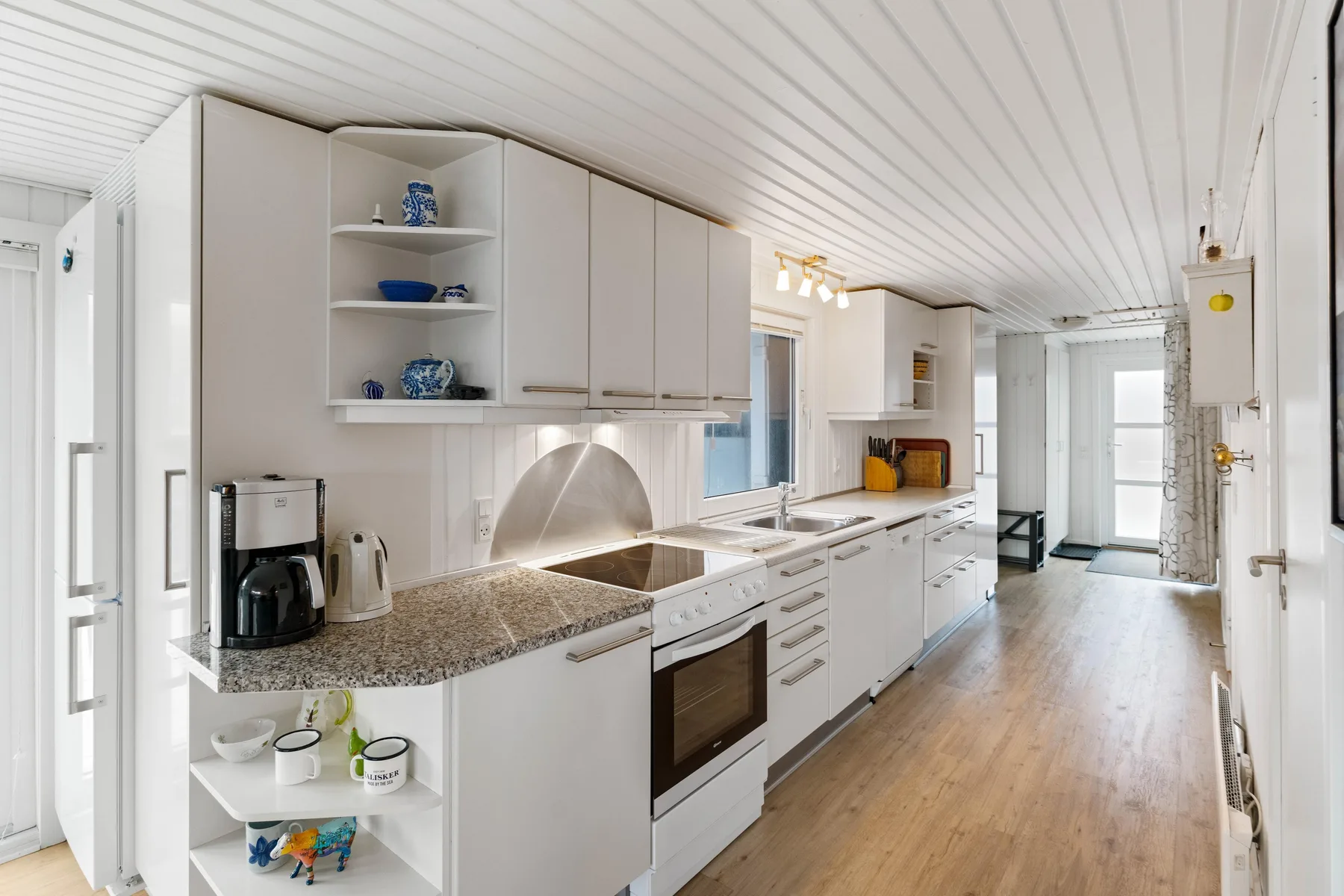 Una cocina luminosa con una encimera larga y armarios blancos.