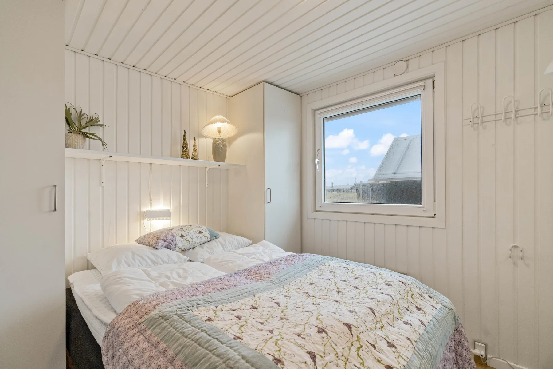 Un dormitorio luminoso con una cama bajo una ventana que da al cielo.