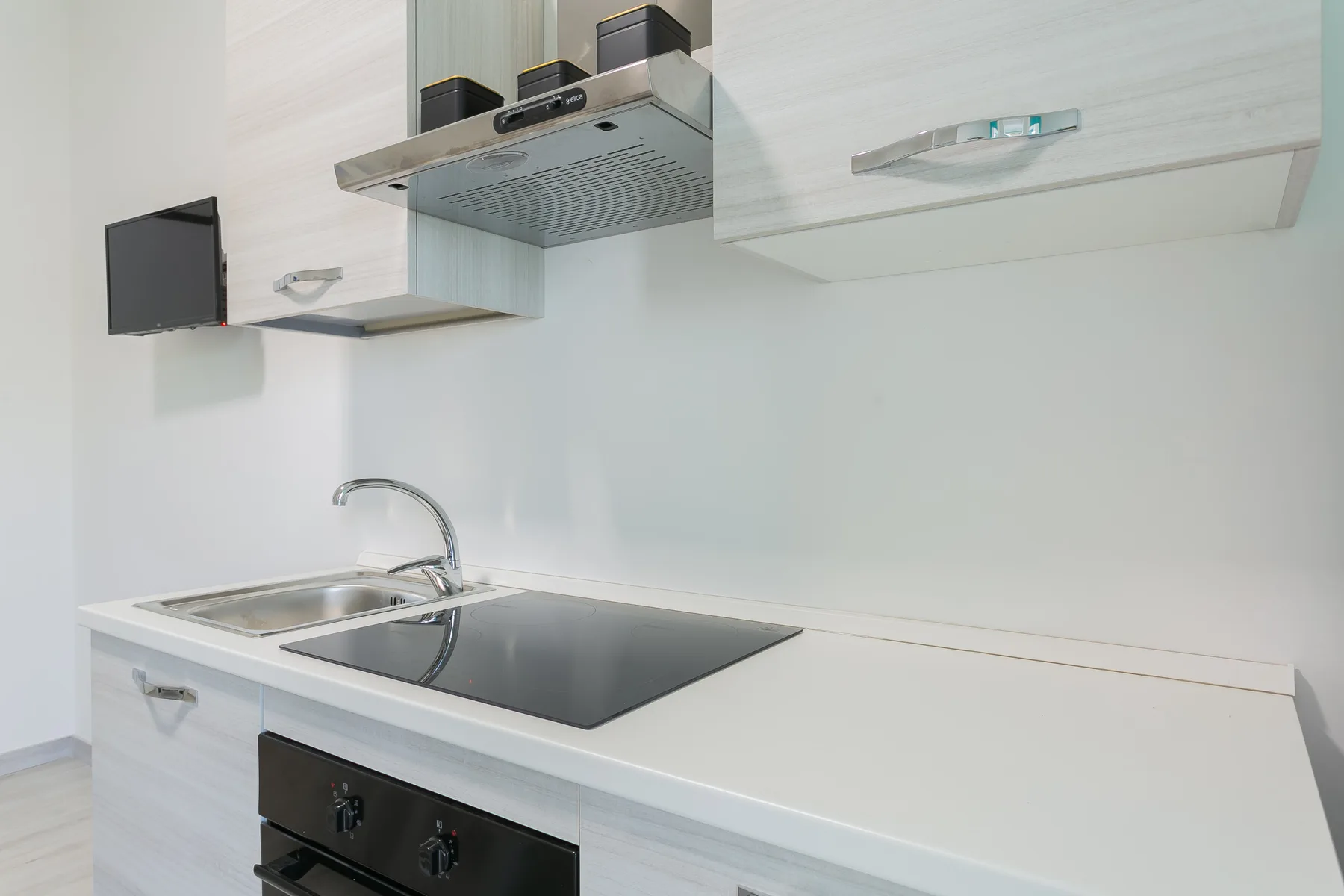 A modern kitchen counter with a sink and a black cooktop.