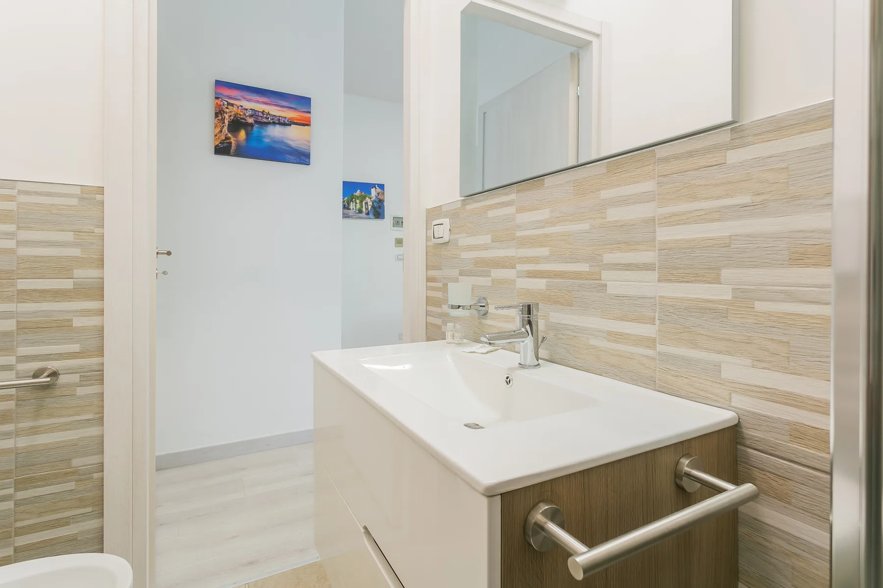 A bathroom vanity with a sink stands beside a tiled wall.