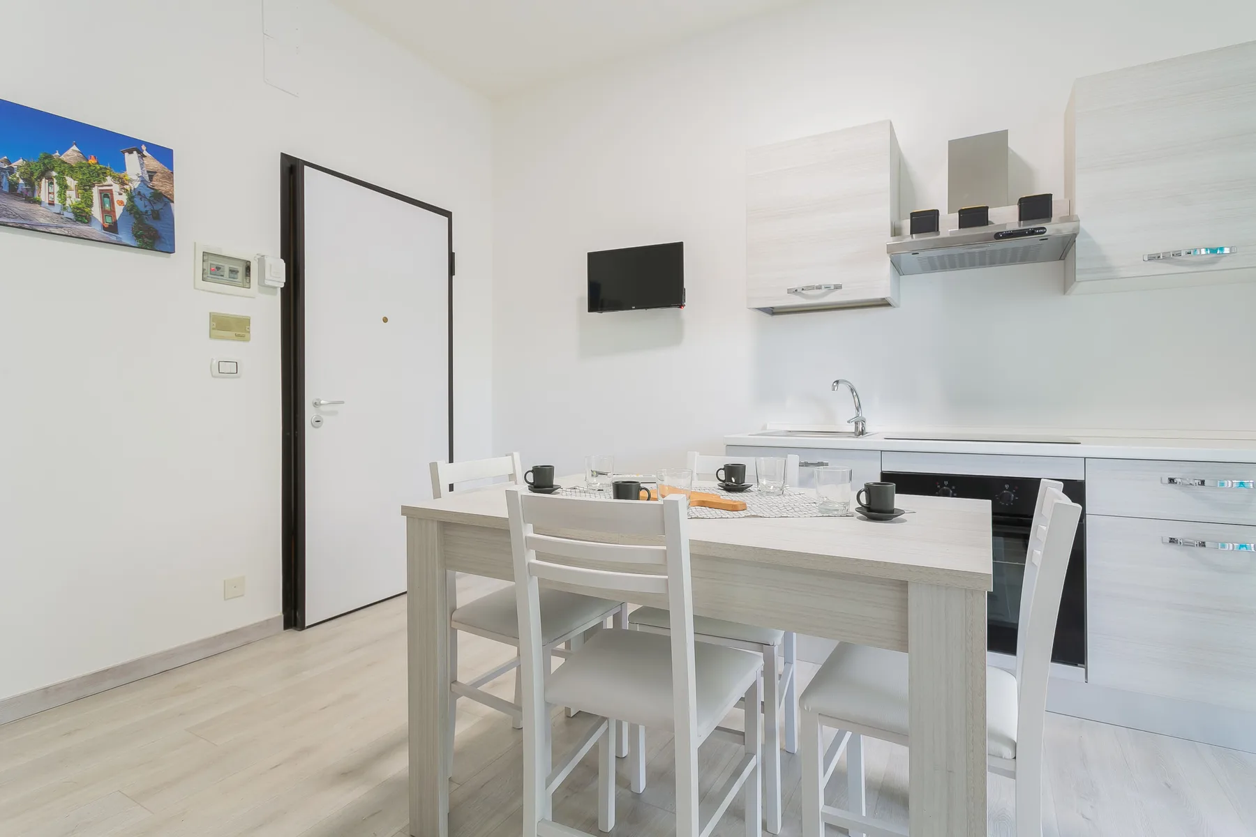 A bright kitchen with a dining table and white seating.