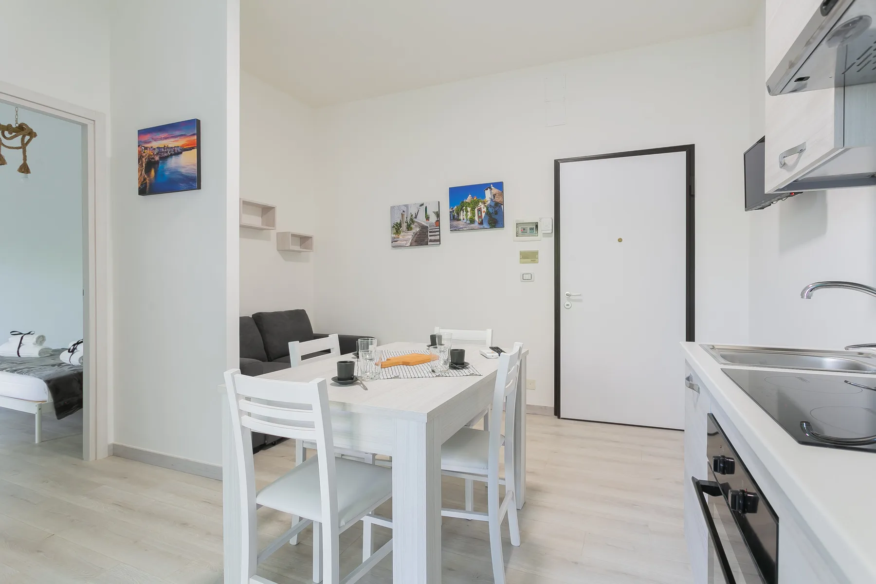 A bright dining area with a white table and chairs beside a compact kitchen.