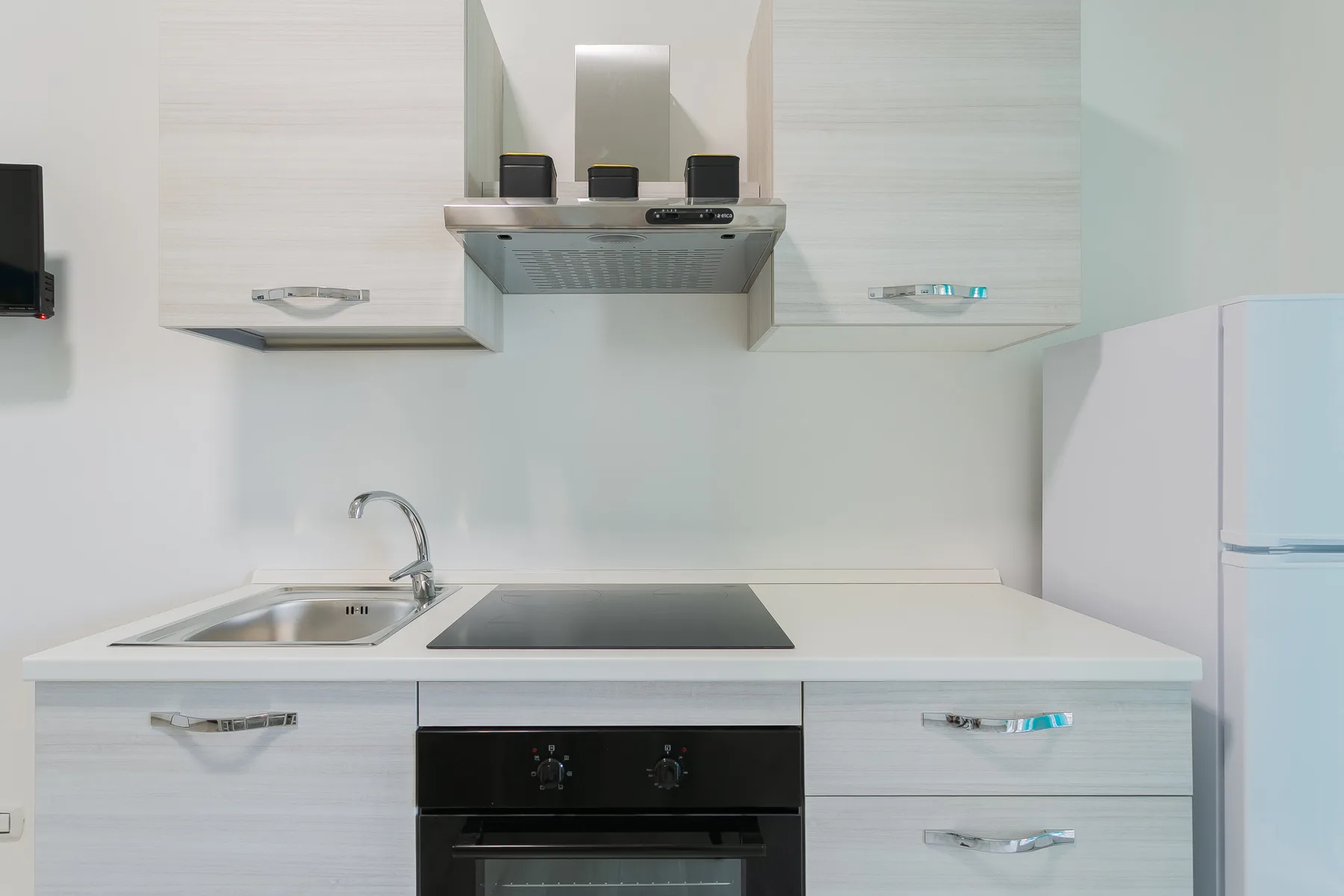 A compact kitchen with a sink, cooktop, and built-in oven.