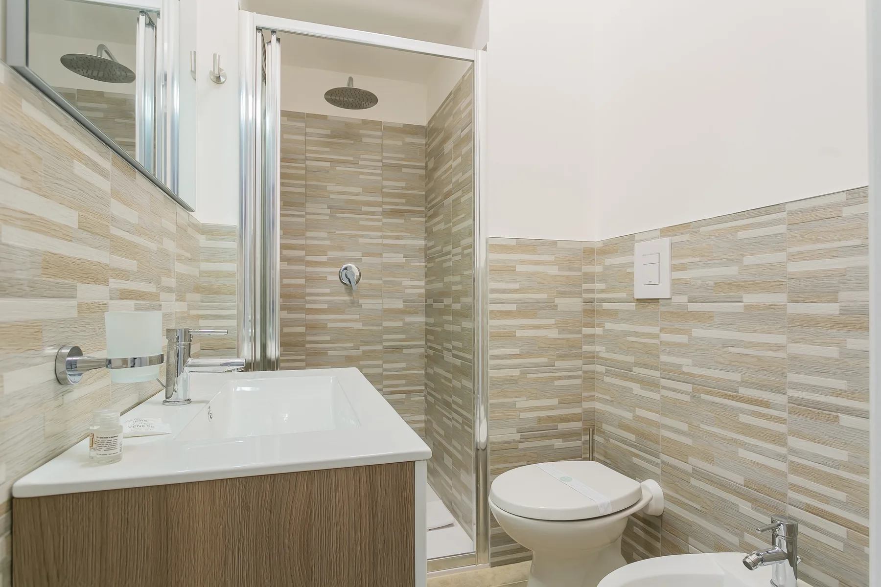 A bathroom with a sink, toilet, and tiled shower area.