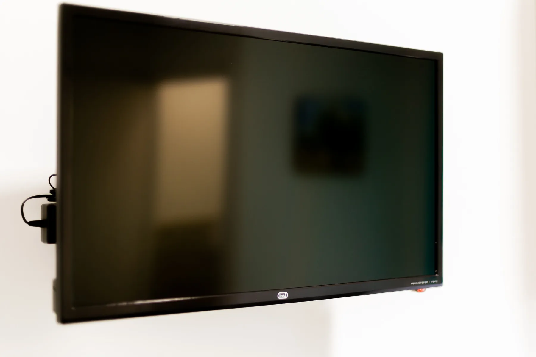 A large flat-screen television is mounted on a white wall.