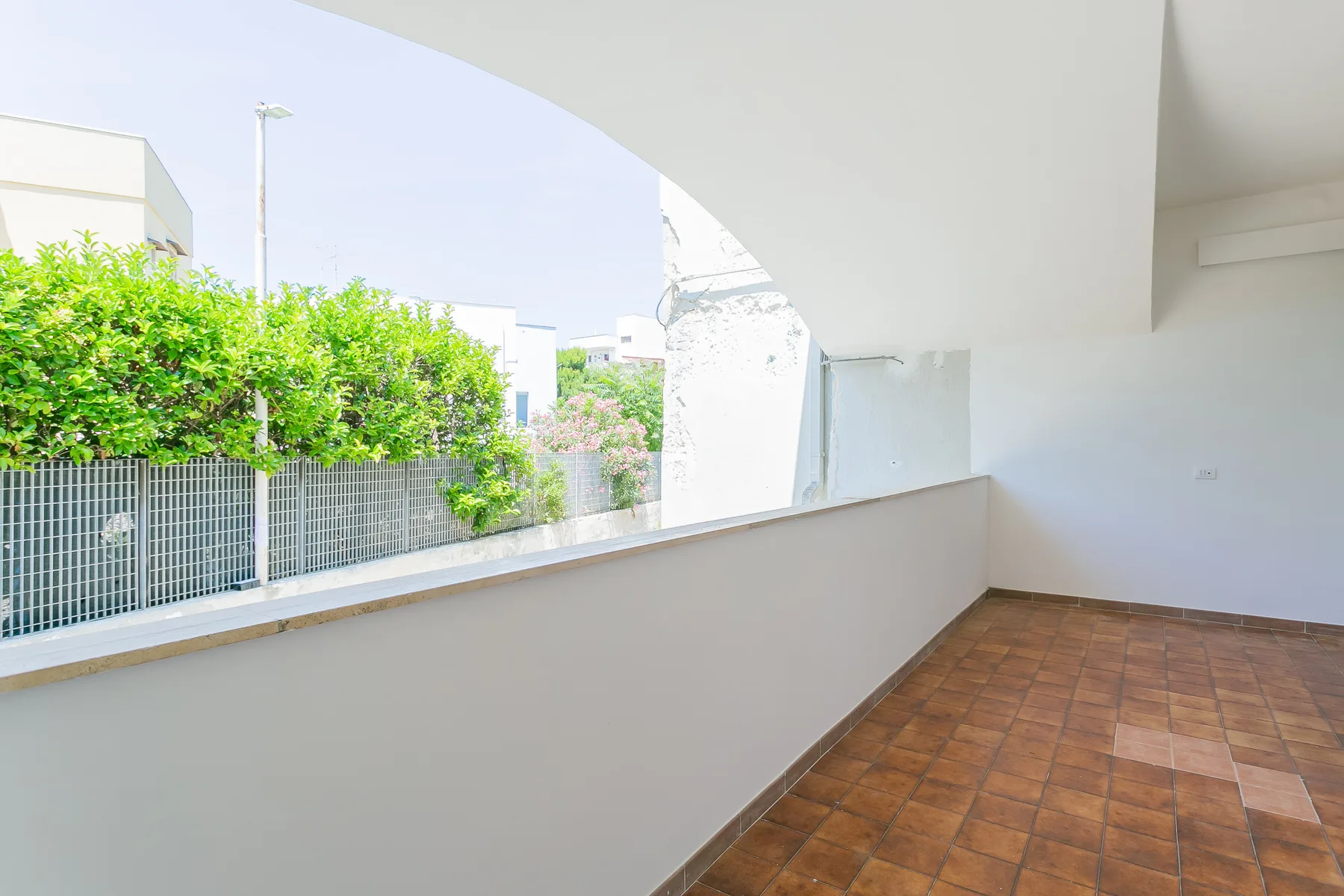 A bright covered patio with a tiled floor and a wide arched opening.