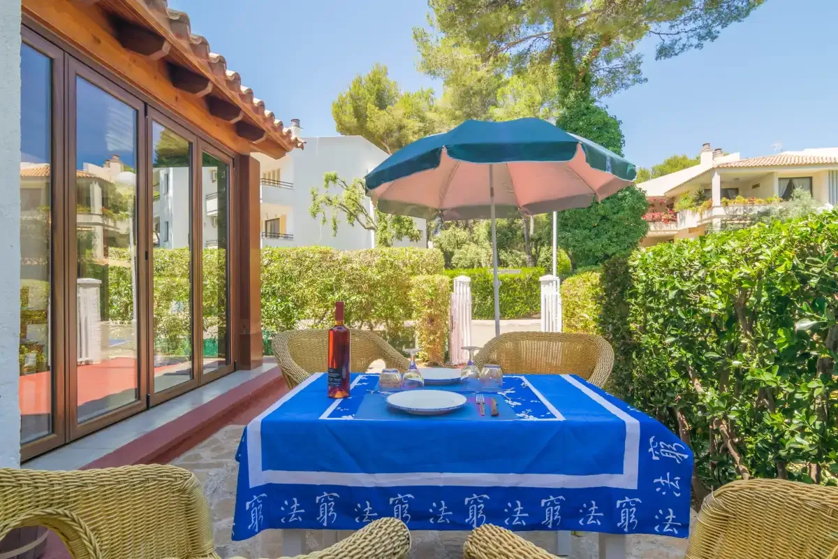 Outdoor dining area with a blue-covered table and patio umbrella.