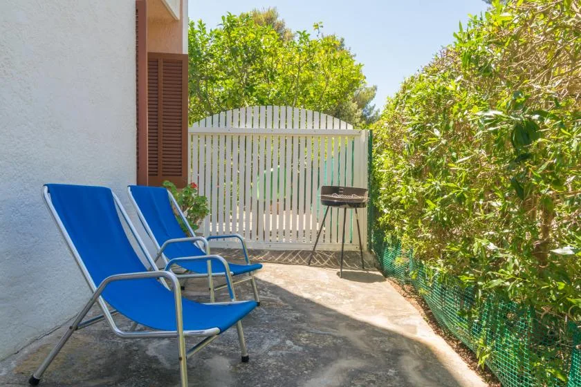 An outdoor patio with blue seating, a white gate, and surrounding greenery.