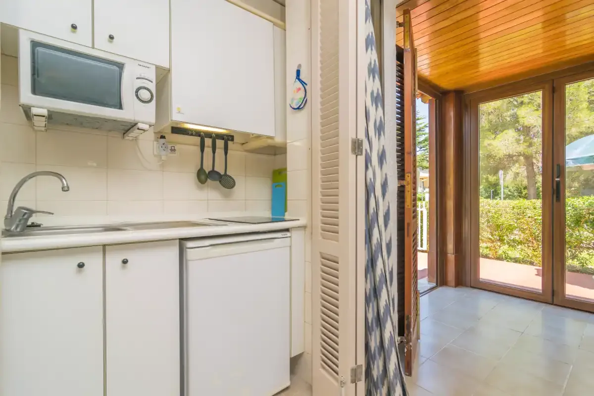 A compact kitchen opens onto a bright room with large glass doors.