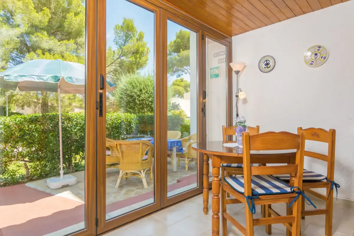 A dining area with wooden seating and a glass door opening onto a garden.
