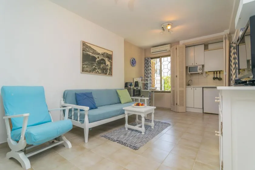 A living area with seating and a small table beside a compact kitchen.