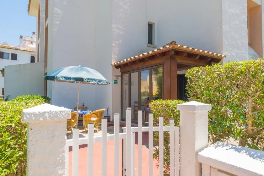 A small outdoor patio with a table, seating, and a blue umbrella beside the building.
