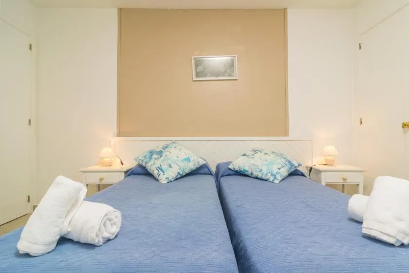 A bedroom with two beds, blue bedding, and matching bedside tables.