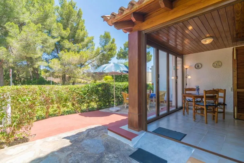 A covered patio opens onto a garden, with a dining table visible inside.