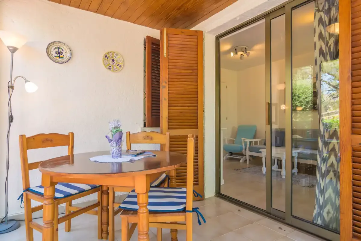 A dining area with a wooden table and chairs beside glass doors.