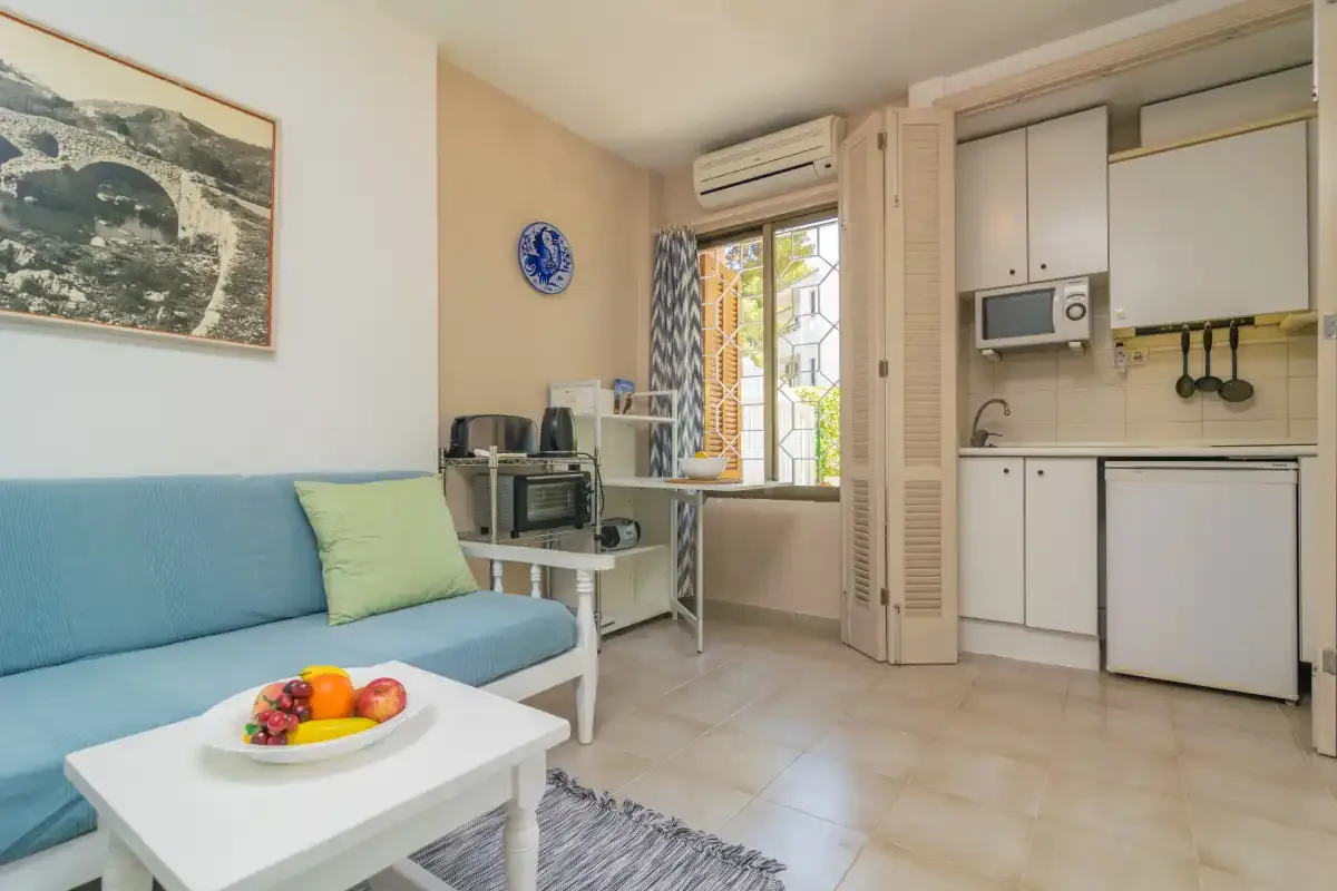 A compact living area with blue seating beside a small kitchen.