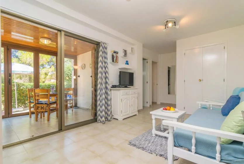 A bright living room with seating, a television, and sliding glass doors to a dining area.
