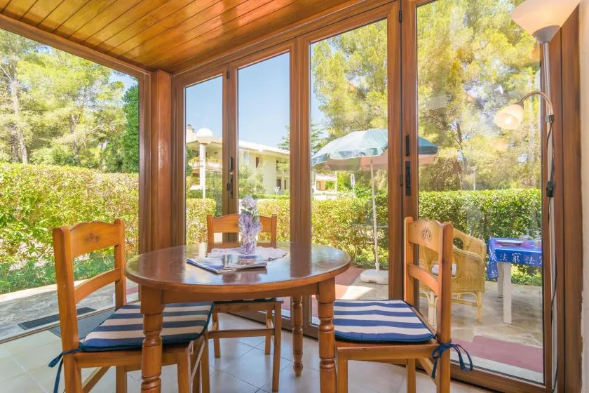 A dining area with a round wooden table beside glass doors overlooking a garden.
