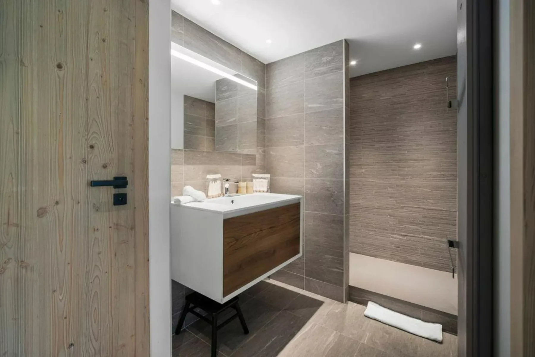 A modern bathroom with a vanity, mirror, and walk-in shower.
