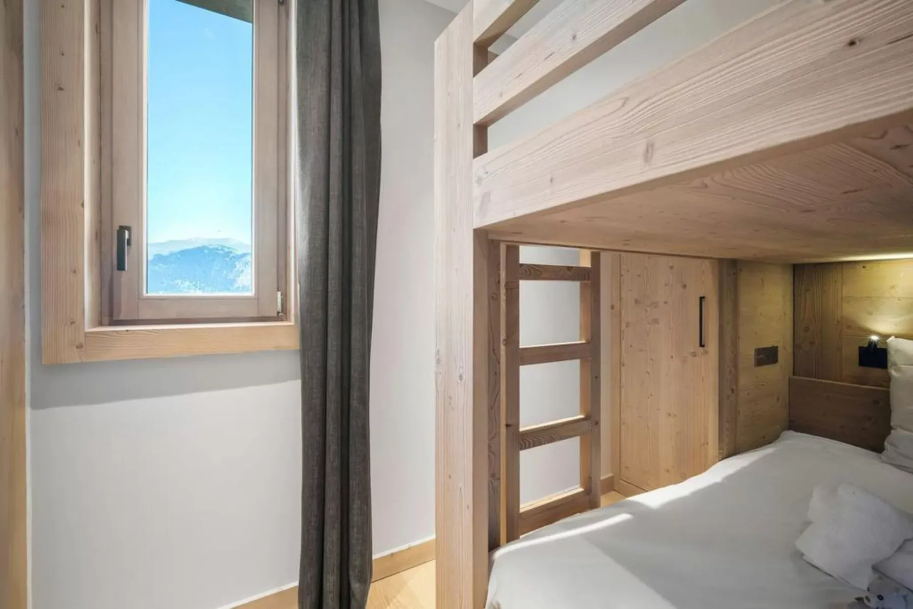 A wood-paneled bedroom with a bunk bed and a window overlooking mountains.