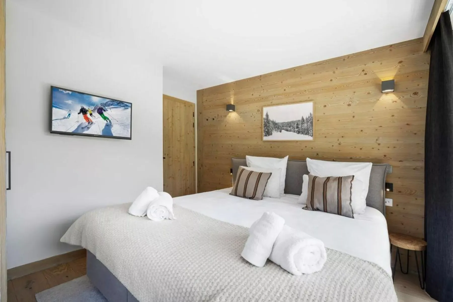 A bedroom with a neatly made bed and wood-paneled walls.