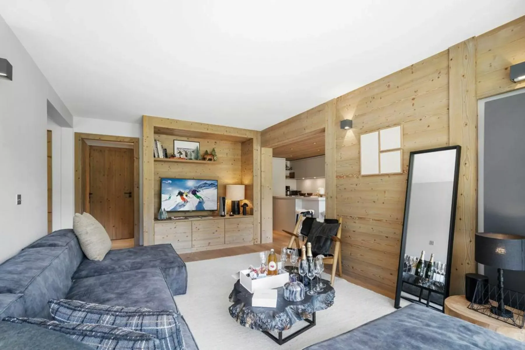 A living room with a television, seating, and light wood-paneled walls.