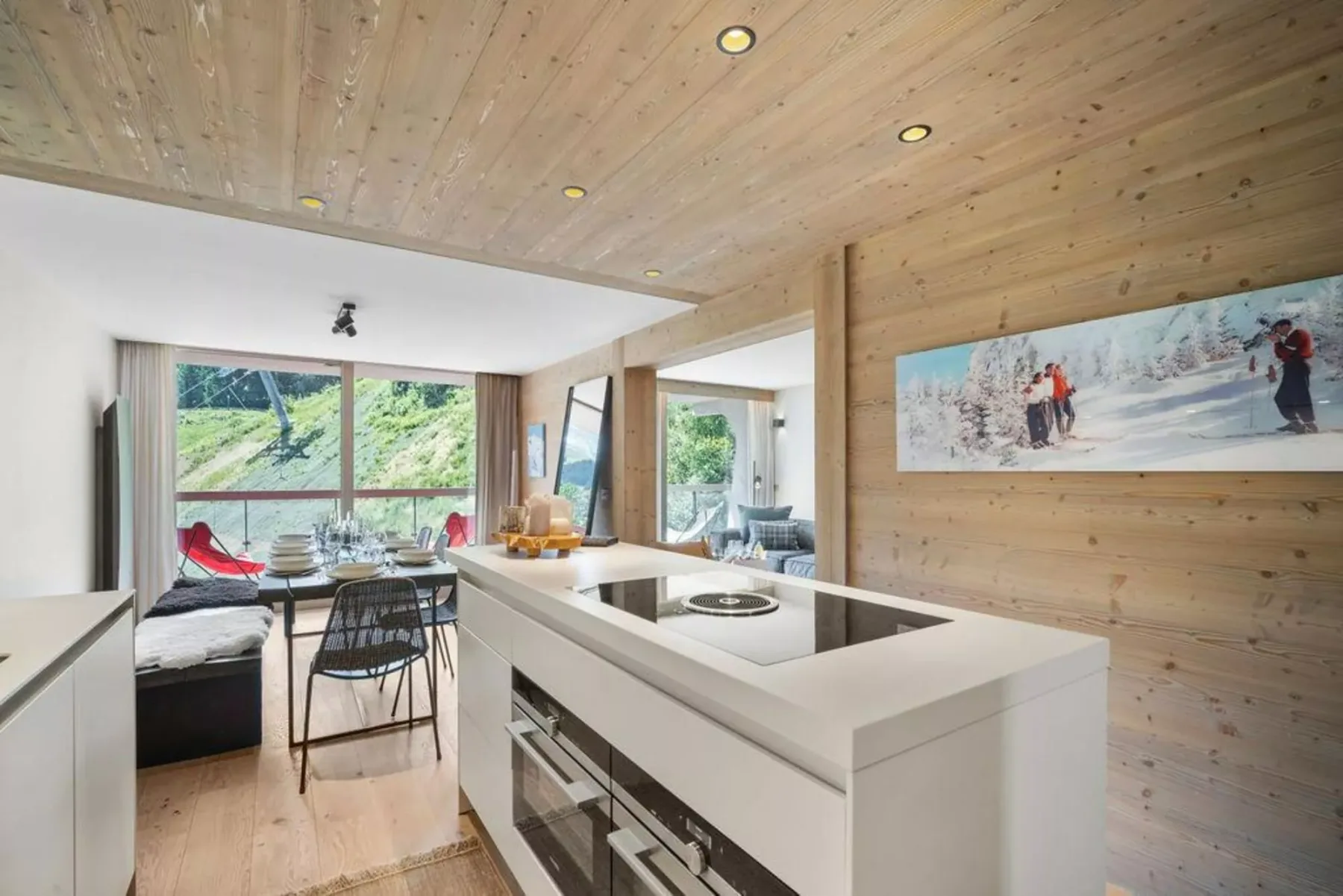 A bright kitchen and dining area with a large island and windows overlooking greenery.