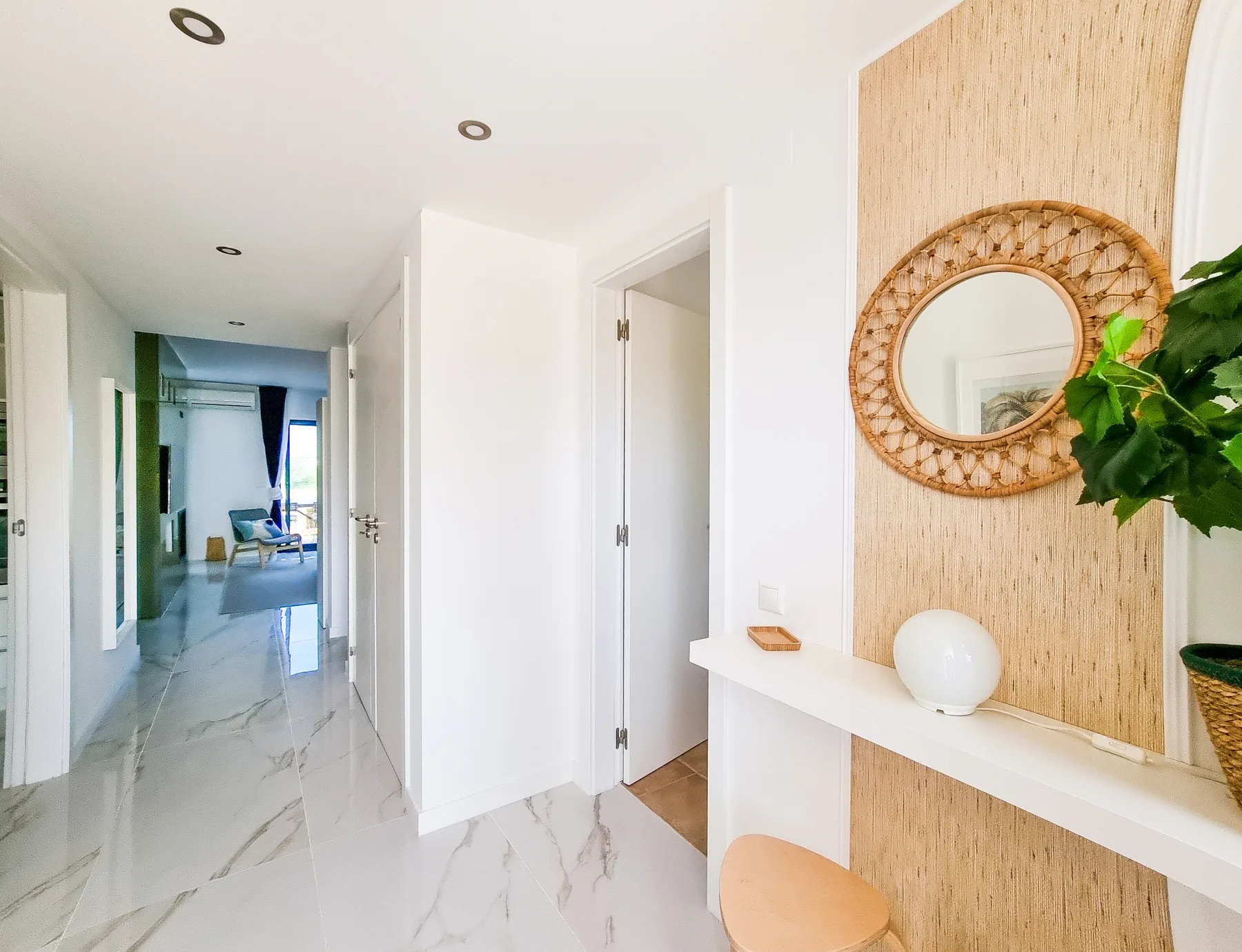 A bright hallway with a white console table and a round mirror.