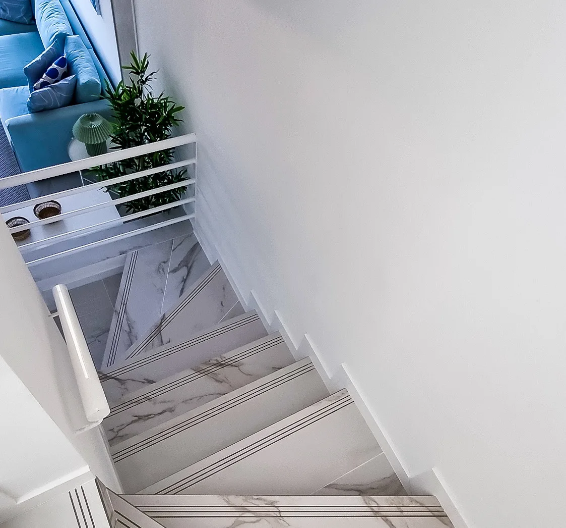Una escalera con peldaños estampados baja junto a una zona de asientos azules.